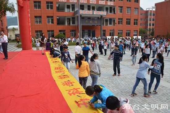 图为学生们在倡议书上签名做承诺