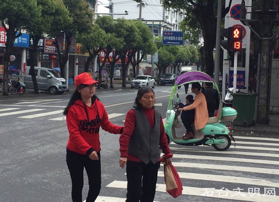 图为志愿者帮助老人过马路