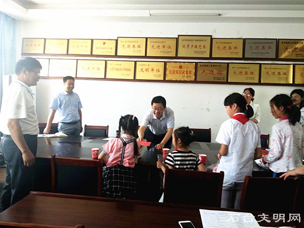 图为李军书记为孩子们送上慰问金