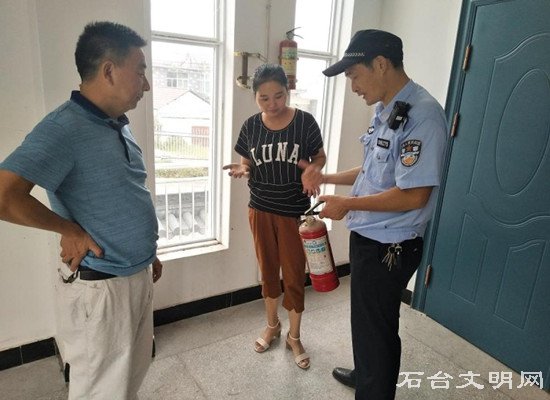 民警在指导学校老师如何正确使用灭火器